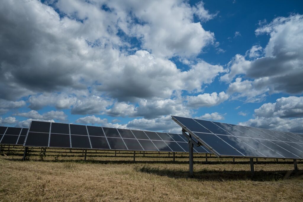 solar panels on a sunny field generating renewable energy under a partly cloudy sky.