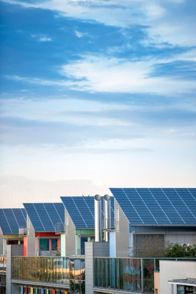Row of modern solar panel homes using clean energy solutions under a bright blue sky.