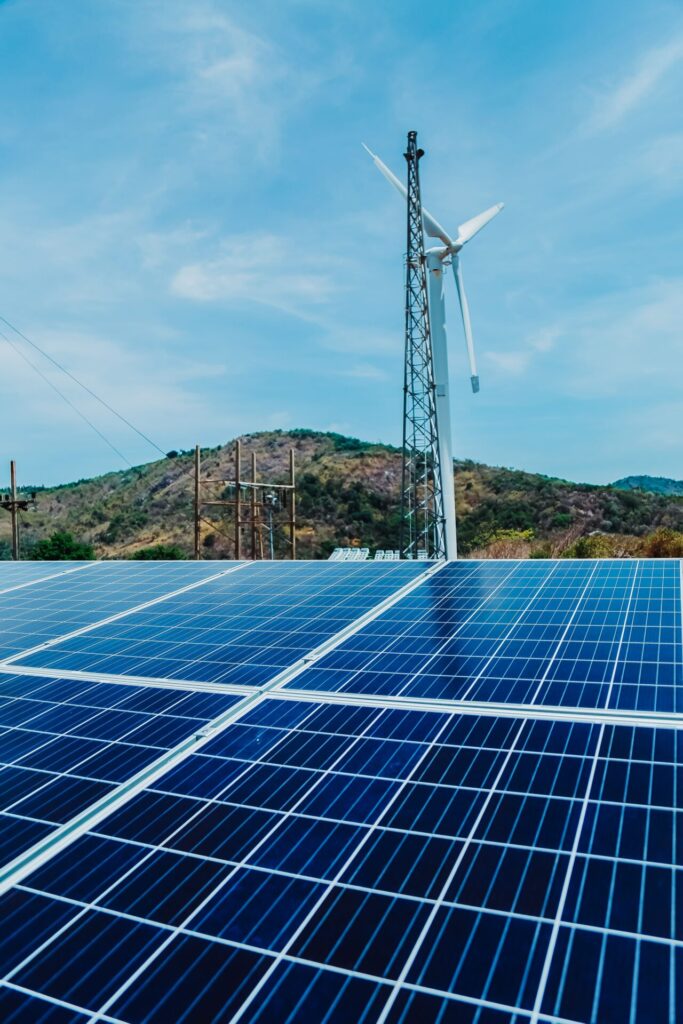 Hybrid renewable energy system with solar panels and wind turbine in a rural landscape.