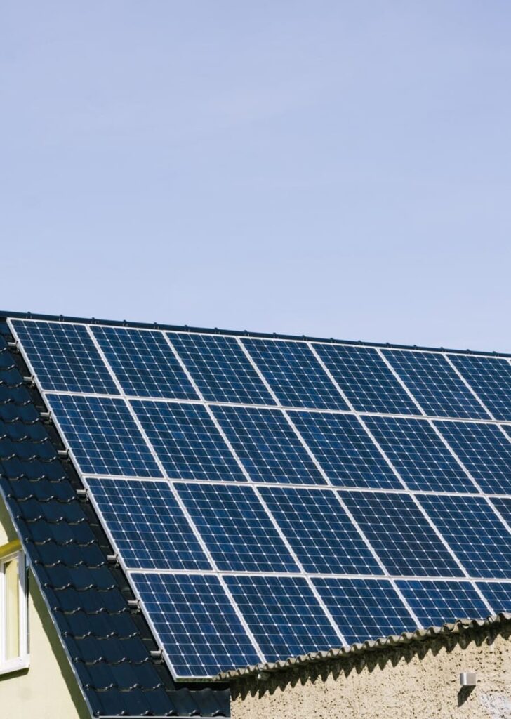 Rooftop solar panel installation on a residential home under clear blue sky – efficient solar energy system for houses.