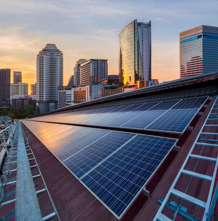 Commercial solar panel installation on a city rooftop during sunset, showcasing sustainable energy solutions for urban buildings.
